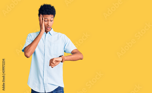 Young african american man wearing casual clothes looking at the watch time worried, afraid of getting late