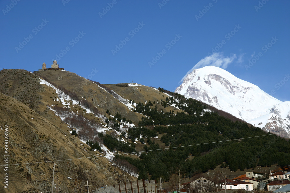 Looking up at the Gergeti Trinity Church on the hill and the snow‐capped Mount Kazbek