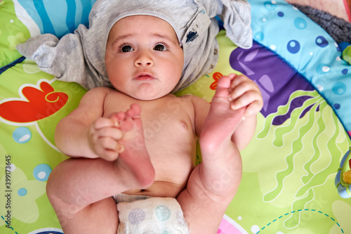 Fotótapéta Caucasian newborn baby semi-naked, with diapers lying on his back on the bed fac
