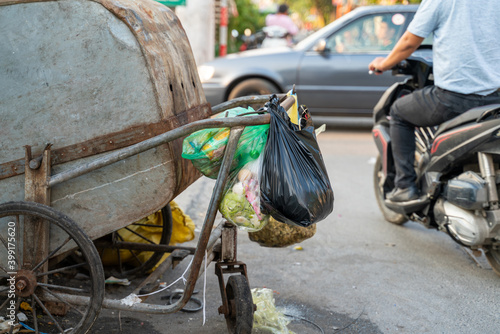 Pile of garbage bags and messy trash on street sidewalk with traffic on background in Hanoi, Vietnam