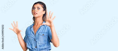 Young beautiful woman wearing casual clothes afraid and terrified with fear expression stop gesture with hands, shouting in shock. panic concept.