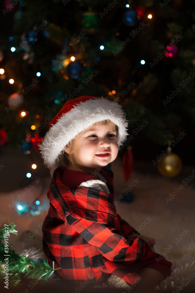 a child in red clothes is sitting waiting for the new year. the concept of celebrating Christmas at midnight. holiday costume a child in red clothes is sitting waiting for the new year. the concept of celebrating Christmas at midnight. holiday costume