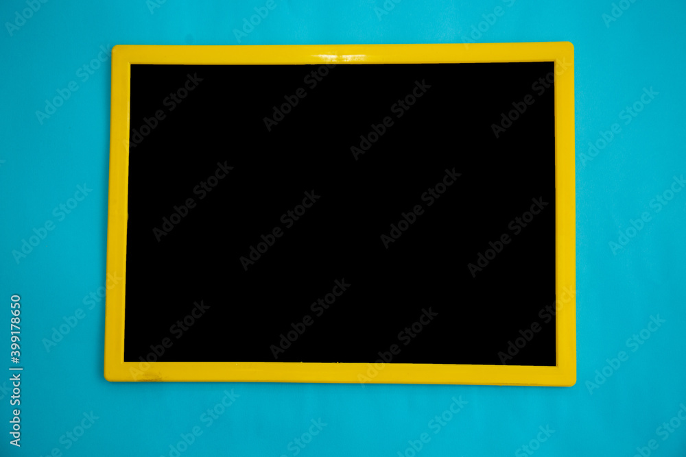 Top view of black chalk board with yellow frame isolated on blue Top view of black chalk board with yellow frame isolated on blue