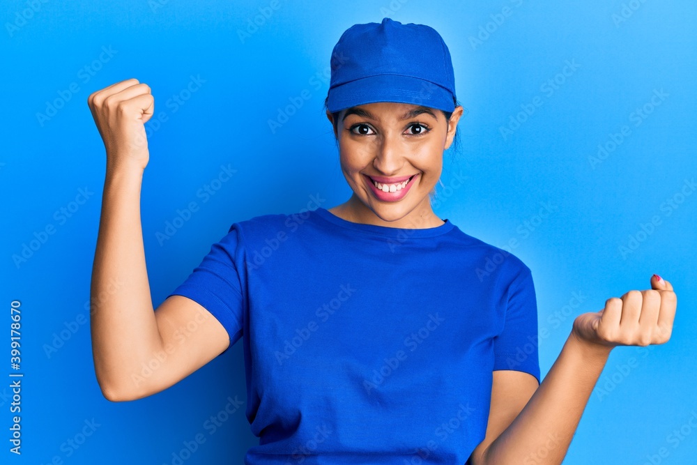 Beautiful brunette woman wearing delivery uniform screaming proud, celebrating victory and success very excited with raised arms