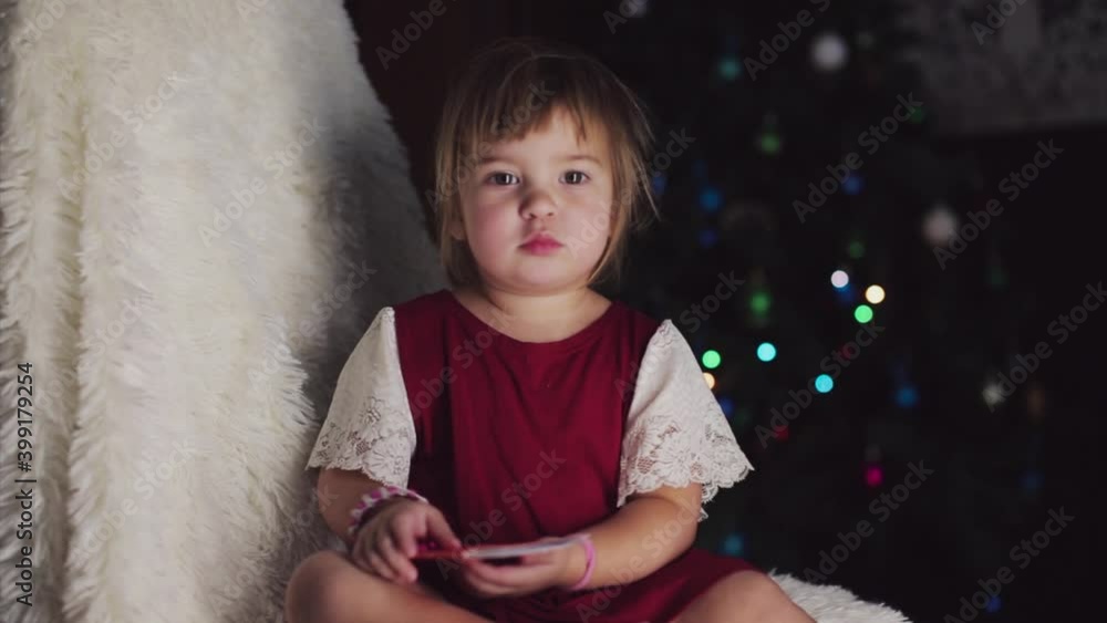 a child in red clothes is sitting waiting for the new year. the concept of celebrating Christmas at midnight. holiday costume. a girl writes a letter to Santa Claus. wish list a child in red clothes is sitting waiting for the new year. the concept of celebrating Christmas at midnight. holiday costume. a girl writes a letter to Santa Claus. wish list