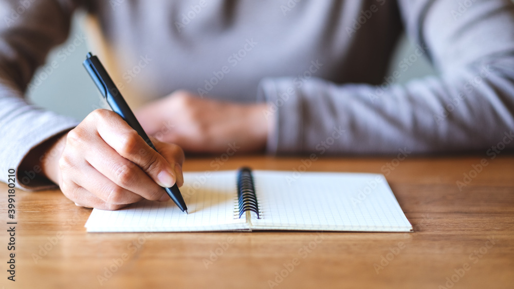Closeup image of a woman writing on a blank notebook on the table Closeup image of a woman writing on a blank notebook on the table