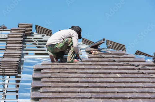 Wallpaper Mural Worker man installing new roof tile on home,selective focus. Torontodigital.ca