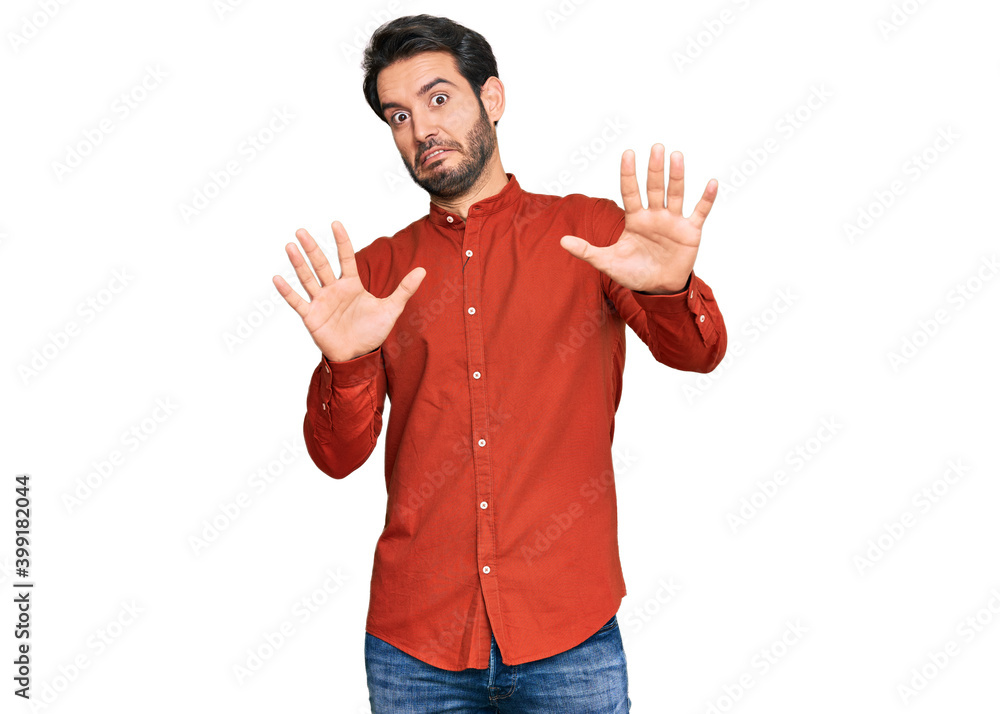 Young hispanic man wearing casual clothes afraid and terrified with fear expression stop gesture with hands, shouting in shock. panic concept. Young hispanic man wearing casual clothes afraid and terrified with fear expression stop gesture with hands, shouting in shock. panic concept.