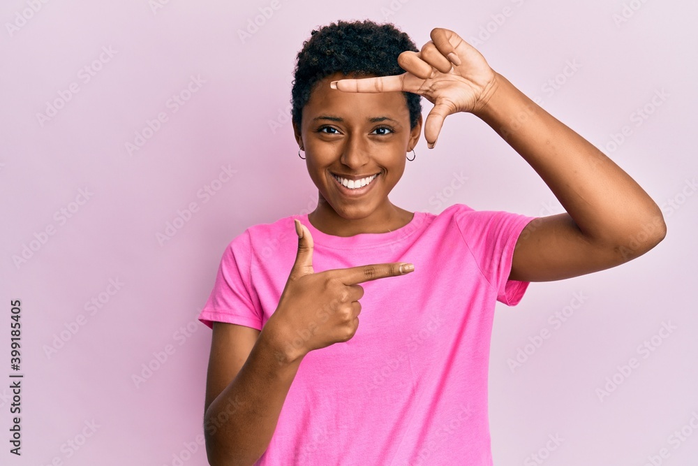 Young african american girl wearing casual clothes smiling making frame with hands and fingers with happy face. creativity and photography concept. Young african american girl wearing casual clothes smiling making frame with hands and fingers with happy face. creativity and photography concept.