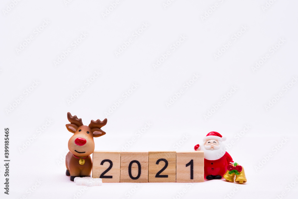 Naklejka premium Happy New Year and Merry Christmas 2021 concept. Ceramic happy Santa Claus and reindeer doll with gold bell standing side wooden text 2021. On isolated white background.