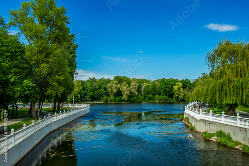 modern green city waterfront walking site summer clear weather day time environment space high trees blue river water and white marble fence architecture object beautiful landmark place © Артём Князь