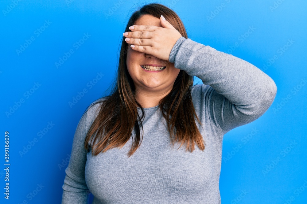 Beautiful brunette plus size woman wearing casual clothes smiling and laughing with hand on face covering eyes for surprise. blind concept. Beautiful brunette plus size woman wearing casual clothes smiling and laughing with hand on face covering eyes for surprise. blind concept.