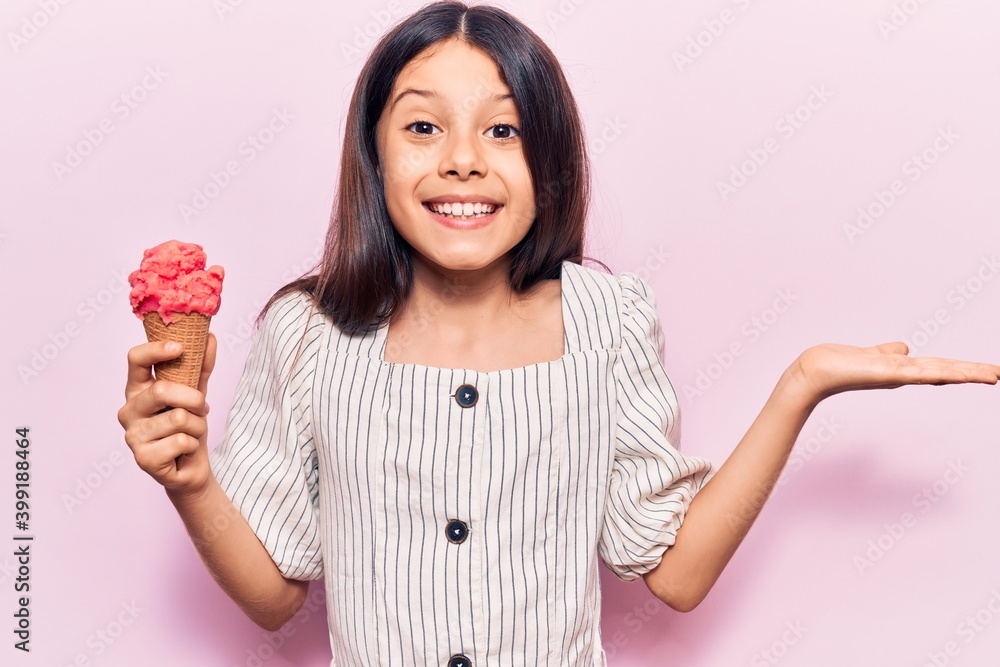 Beautiful child girl holding ice cream celebrating victory with happy smile and winner expression with raised hands Beautiful child girl holding ice cream celebrating victory with happy smile and winner expression with raised hands