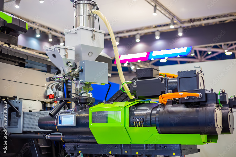 Automatic plastic injection molding machine during work at exhibition, trade show. Manufacturing, production, technology concept Automatic plastic injection molding machine during work at exhibition, trade show. Manufacturing, production, technology concept