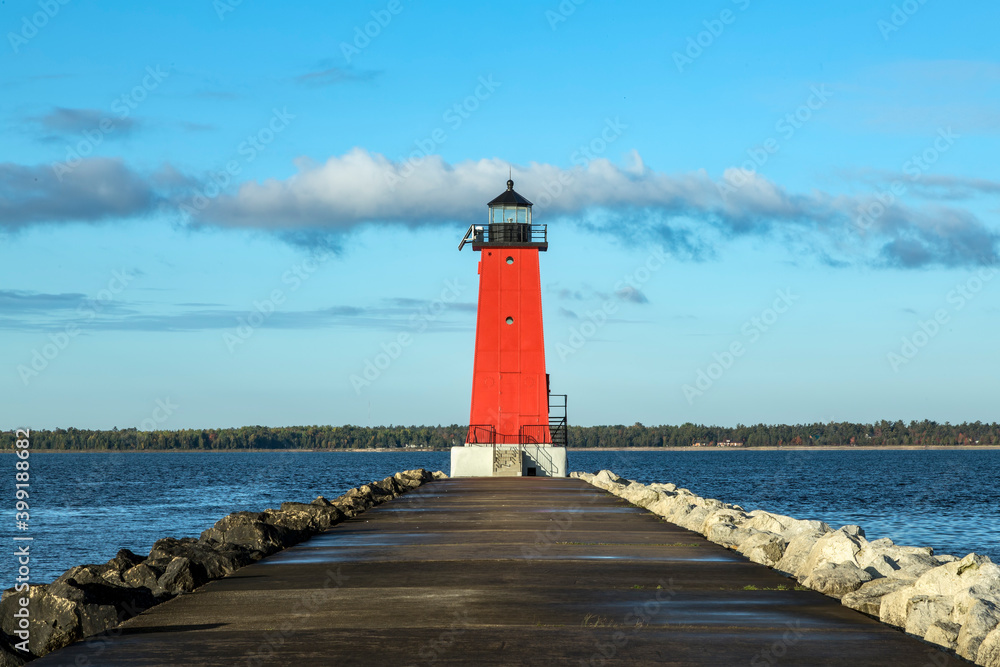 A pier leads up to the bright red Manistique Lighthouse, and landmark on the Lake Michigan coast of the Upper Peninsula of Michigan.