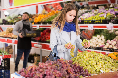 Female shopper picks grape at grocery store. High quality photo