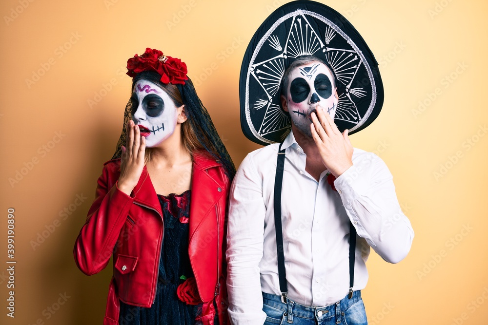 Couple wearing day of the dead costume over yellow bored yawning tired covering mouth with hand. restless and sleepiness. Couple wearing day of the dead costume over yellow bored yawning tired covering mouth with hand. restless and sleepiness.