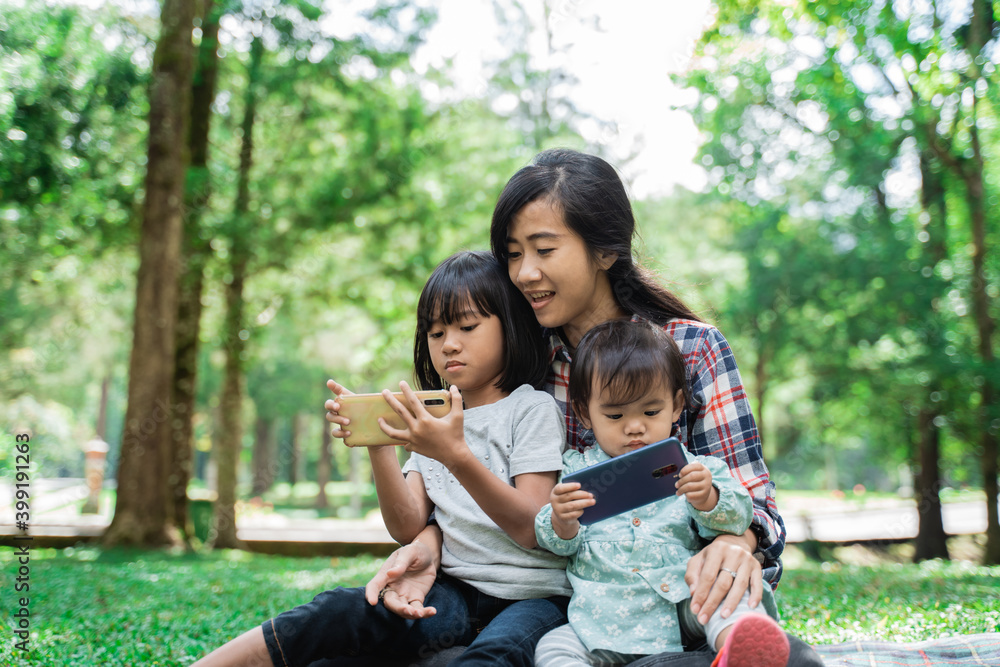 Portrait of a mother accompanying her child to play cellphones in the park Portrait of a mother accompanying her child to play cellphones in the park