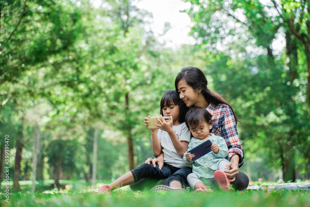 Portrait of a mother accompanying her child to play cellphones in the park Portrait of a mother accompanying her child to play cellphones in the park