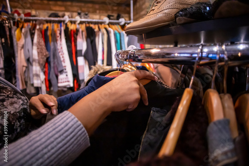 African American black woman with curly hair is shopping for clothing at a local shop. she is browsing through many pretty items to purchase at a good discount