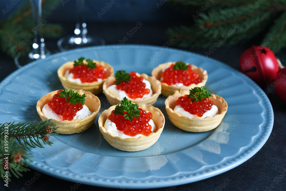 Tartlets with cream cheese and red caviar on a beautiful plate on the New Year's table. New Year's snack. Tartlets with cream cheese and red caviar on a beautiful plate on the New Year's table. New Year's snack.