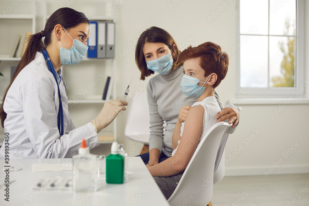 Scared little child makes funny face when he sees syringe needle in nurse's hand Scared little child makes funny face when he sees syringe needle in nurse's hand