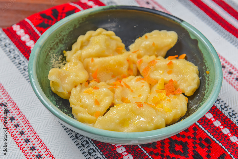 Dumplings, filled with mashed potato in plate on traditional Ukrainian tablecloth. Varenyky, vareniki, pierogi, pyrohy. Dumplings, filled with mashed potato in plate on traditional Ukrainian tablecloth. Varenyky, vareniki, pierogi, pyrohy.