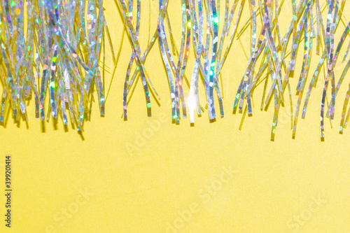 Foto silver holographic tinsel fringe on an illuminating yellow background