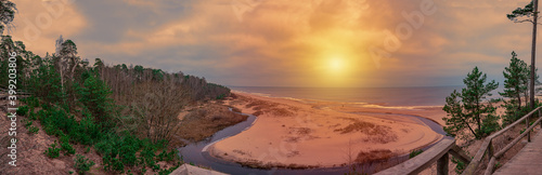 Panorama view of white sand beach and sunset over Baltic sea surrounded by conifer trees forest in Latvia. The White Dune and Baltic see at Saulkrasti in autumn. Sunset panorama.