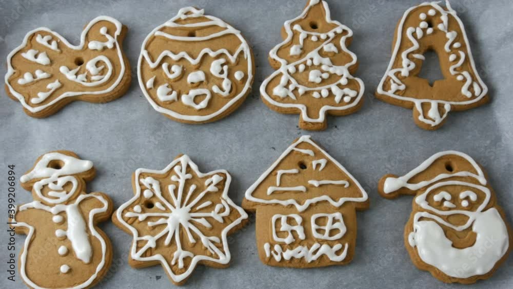 Christmas holiday gingerbread cookie. A row of beautifully decorated with white icing Christmas gingerbread in the shape of a snowman, snowflake, house, Christmas tree toy, bird, bell in home kitchen. Christmas holiday gingerbread cookie. A row of beautifully decorated with white icing Christmas gingerbread in the shape of a snowman, snowflake, house, Christmas tree toy, bird, bell in home kitchen.