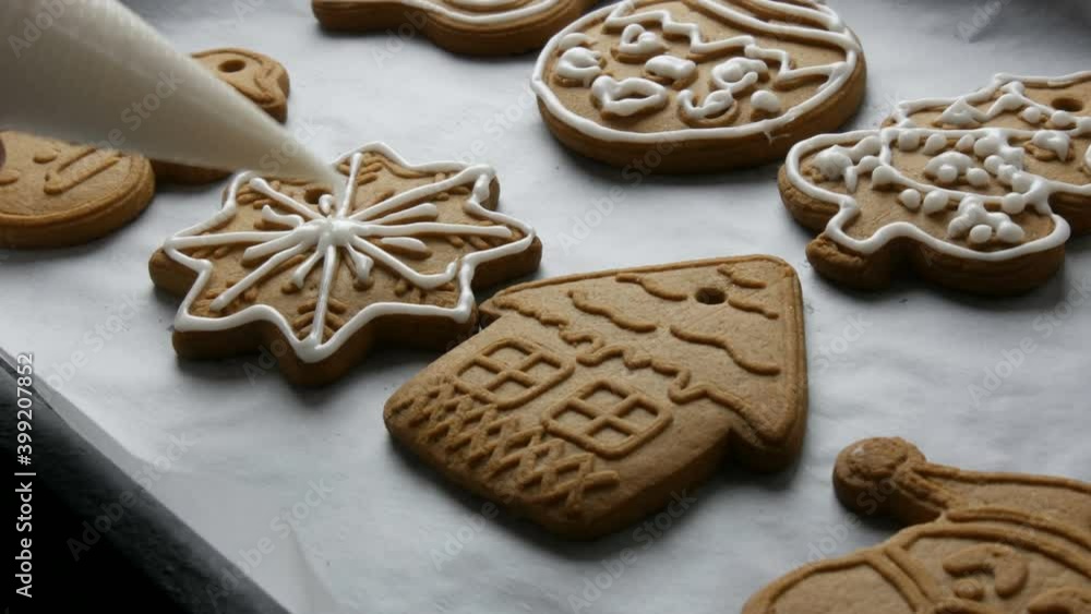 Christmas holiday gingerbread cookie. Woman's hand decorating a pastry bag with sweet white icing cookies in the shape of a beautiful snowflake at home kitchen. Christmas holiday gingerbread cookie. Woman's hand decorating a pastry bag with sweet white icing cookies in the shape of a beautiful snowflake at home kitchen.