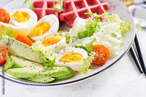 Breakfast with beetroot waffles, boiled egg, tomato and slice avocado on white background. Appetizers, snack, brunch. Healthy food.