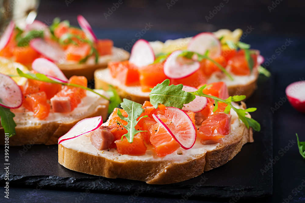 Sandwich with salted salmon for healthy breakfast on dark background. Fish menu. Sandwich with salted salmon for healthy breakfast on dark background. Fish menu.