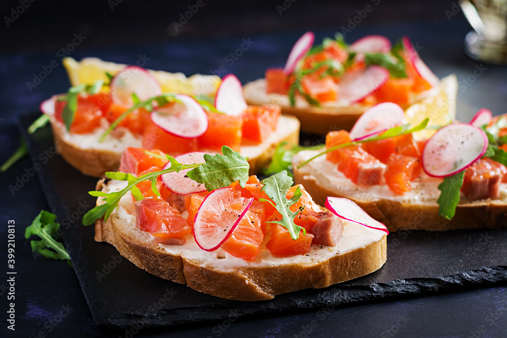 Sandwich with salted salmon for healthy breakfast on dark background. Fish menu. Sandwich with salted salmon for healthy breakfast on dark background. Fish menu.