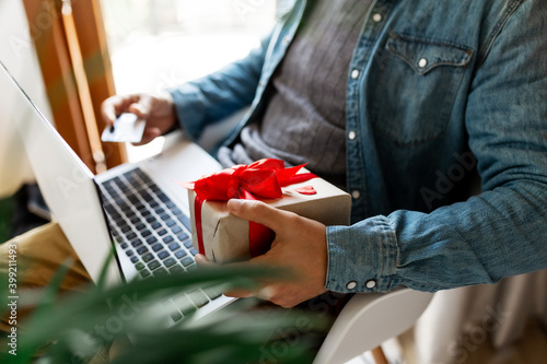 Man using laptop computer and credit card, ordering gifts for Valentines day, Womans Day, Christmas. Shopping online
