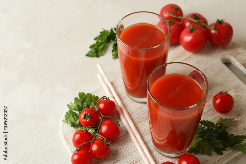 Board with tomato juice and tomatoes on white textured background Board with tomato juice and tomatoes on white textured background