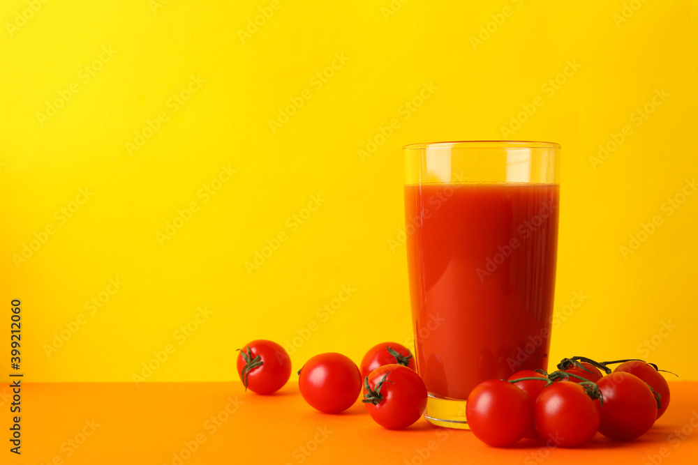 Glass of tomato juice and tomatoes against yellow background Glass of tomato juice and tomatoes against yellow background