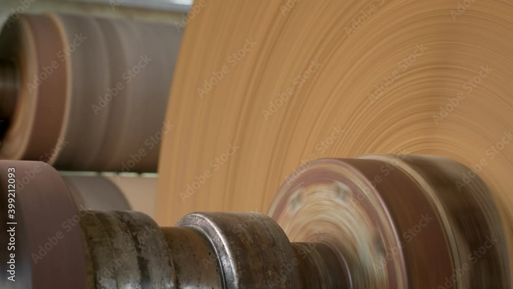 Large bobbin of packaging paper rotates on old metal roll