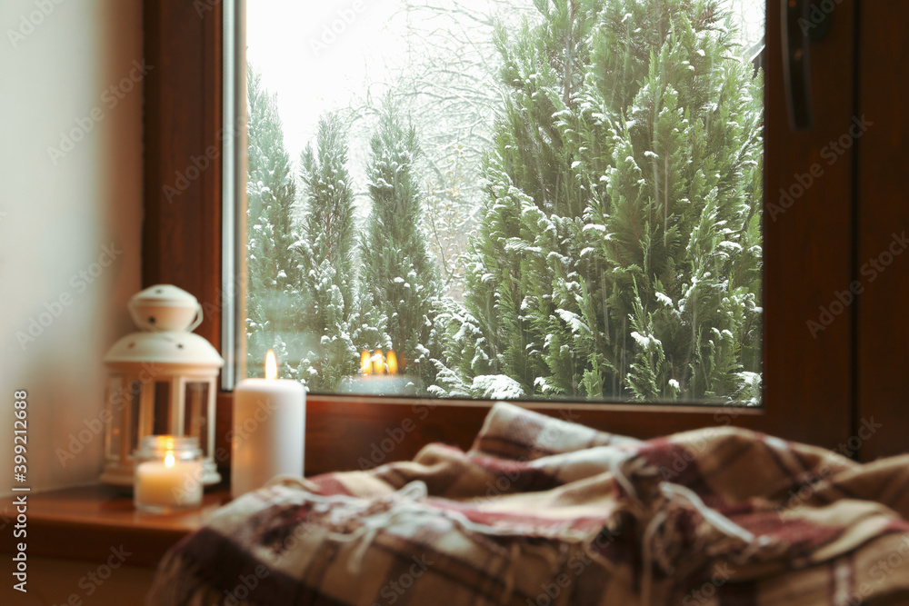 Plaid, candles and lantern on wooden windowsill Plaid, candles and lantern on wooden windowsill