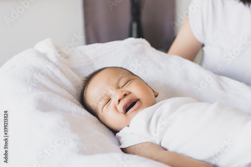 Adorable little asian newborn baby laughing and lying on a comfortable bed