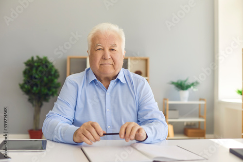 Senior businessman worker sitting and looking at camera at desk