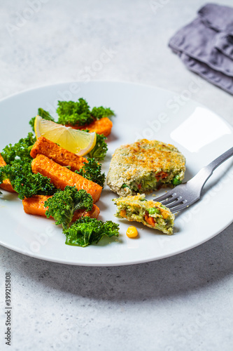 Vegetarian food concept. Vegetable fritter with baked sweet potato and kale on white plate.