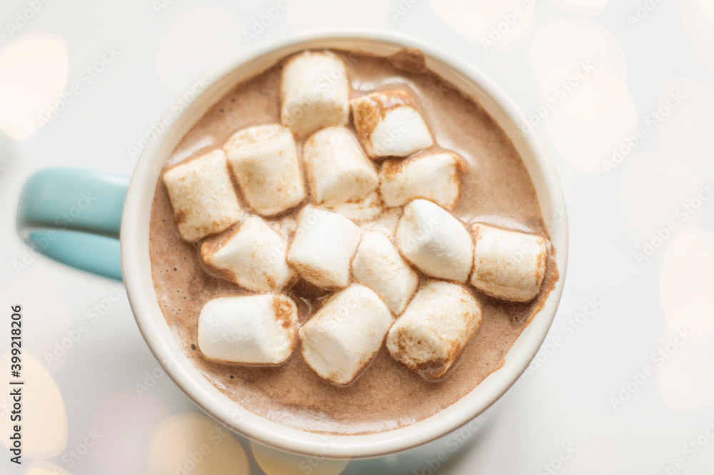 A mug of chocolate drink with marshmallows on a light background with bokeh. A mug of chocolate drink with marshmallows on a light background with bokeh.