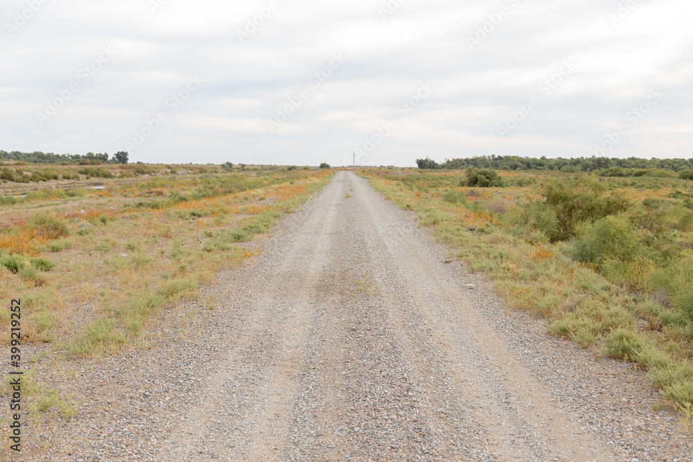 Dirty, dusty, gravel road in the steppe on a sunny bright summer day.