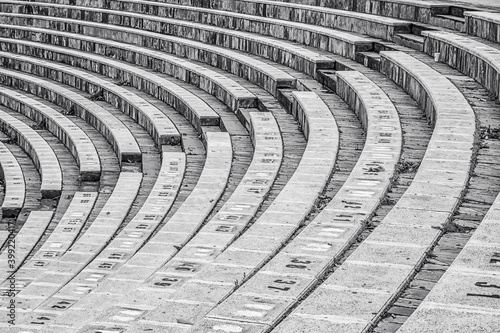 Amphitheater in Coslada. Side view highlighting the geometry of the curved line of the construction, with the stairs to descend on the diagonal of the image. Black and white