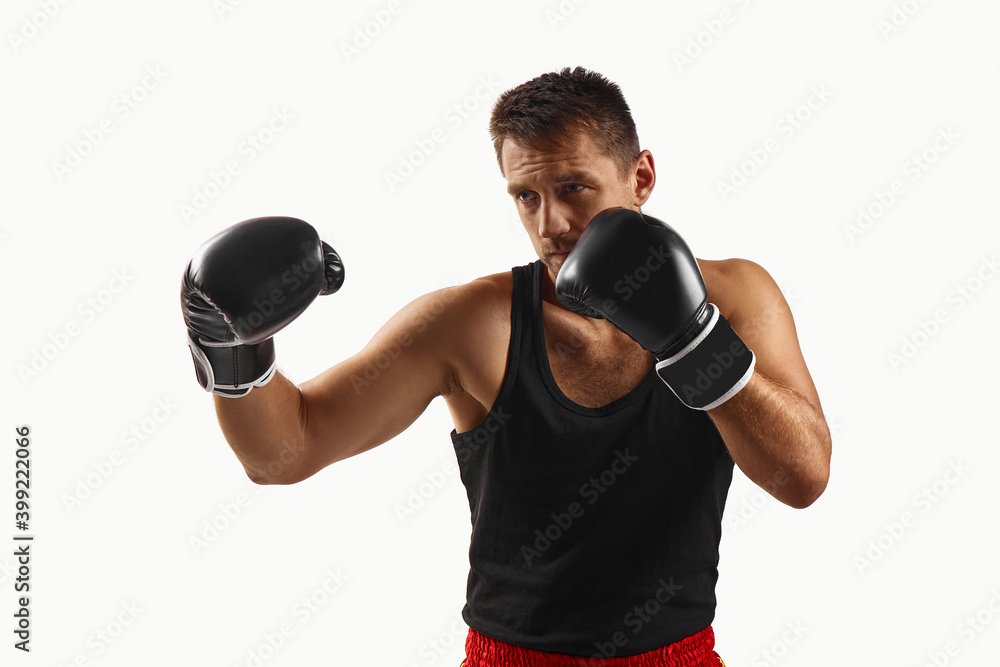 Handsome muscular man in black boxing gloves punching isolated on white background.