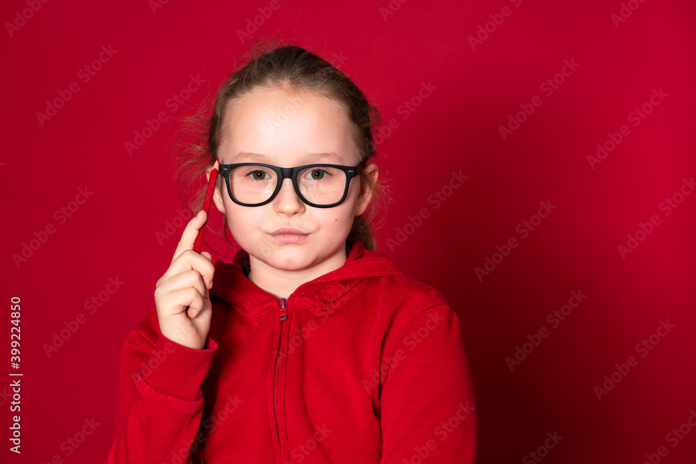 pretty young school girl with red pencil and red sweater is standing in front of a red background
