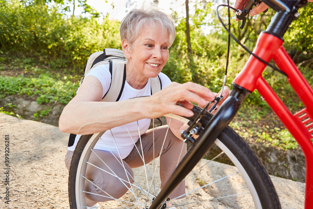 Obraz premium Senior woman doing DIY repair of bicycle