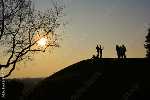 Silhouettes of people standing on top of the hill at colorful sunset doing a photoshoot with beautiful background of sun and monument  of Victory  Pobednik  on Kalemegdan  Belgrade  Serbia.