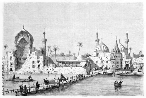 pontoon bridge on river in Baghdad warm cityscape with arabian architecture houses. Ancient grey tone etching style art by Rord�, Le Tour du Monde, 1861 photo